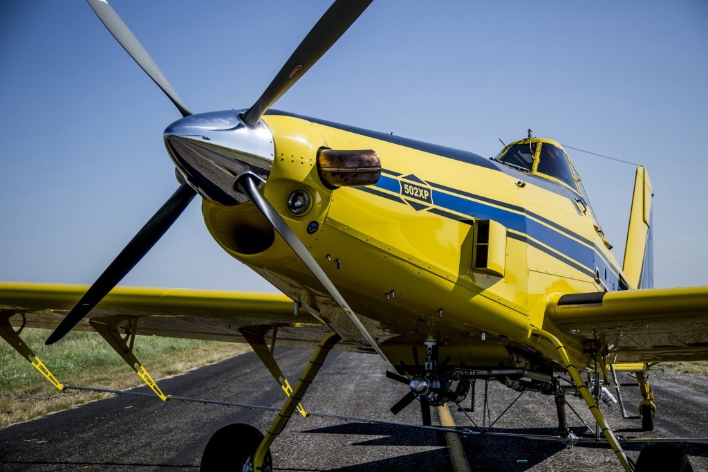 Photograph of a yellow-and-blue agricultural aircraft on a rural ramp